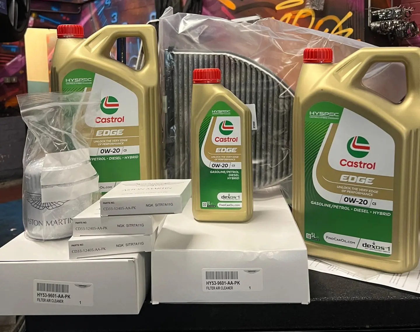 Genuine parts laid out ready for the Aston Martin DBS Superleggera service: Castrol Supercar engine oil, Aston Martin oil and air filters, and 12 NGK spark plugs